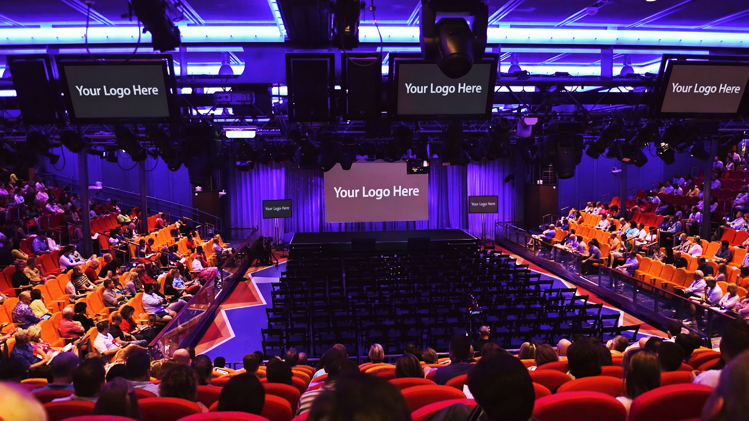 Studio B in conference mode with MAXCON 2027 on the center stage LED screen and three overhead monitors